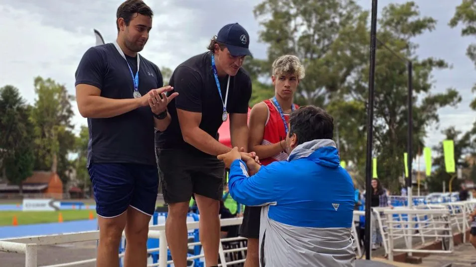 Juan Arrieguez  recibe la medalla de parte su entrenador, el azuleño Julio Piñero.